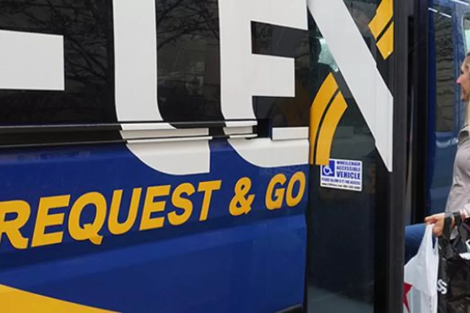 Blue FLEX bus with "Request & Go" text on side, woman rider boarding